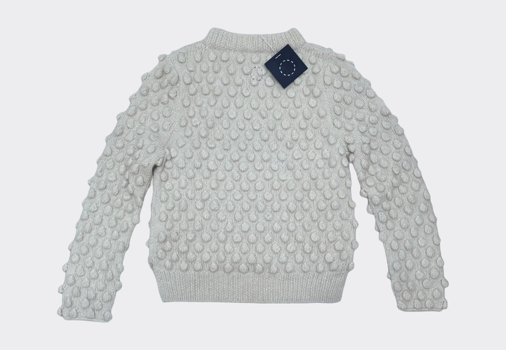 White beige knit sweater with textured bobble pattern on a light gray background