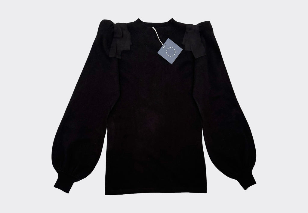 Black cashmere sweater with ruffled sleeves on a light gray background