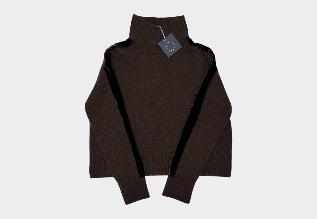 Brown turtleneck sweater with velvet stripe on sleeves and a navy swing tag on a light gray background