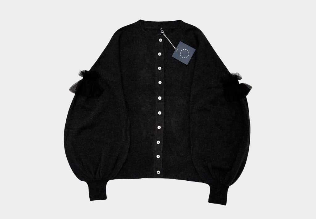 Dark Grey round neck cardigan with light coloured buttons, dropped shoulder and bulbous lower sleeves with tulle velvet detail on a light gray background