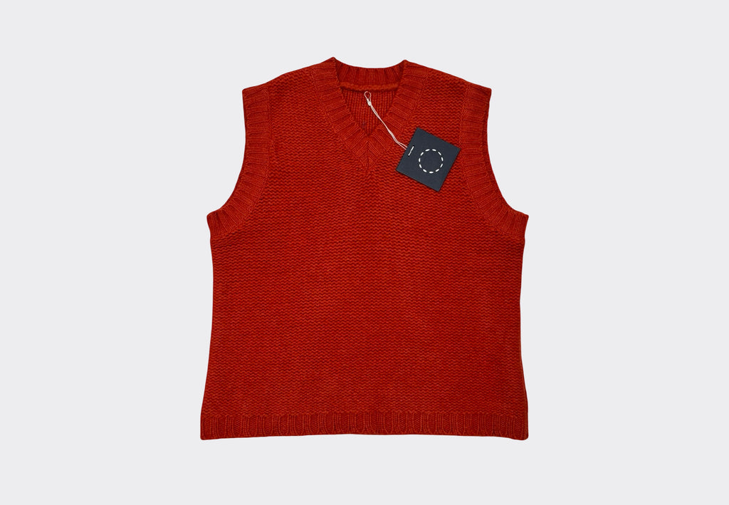 Red sleeveless v neck knitted sweater vest with a tag on a light gray background 