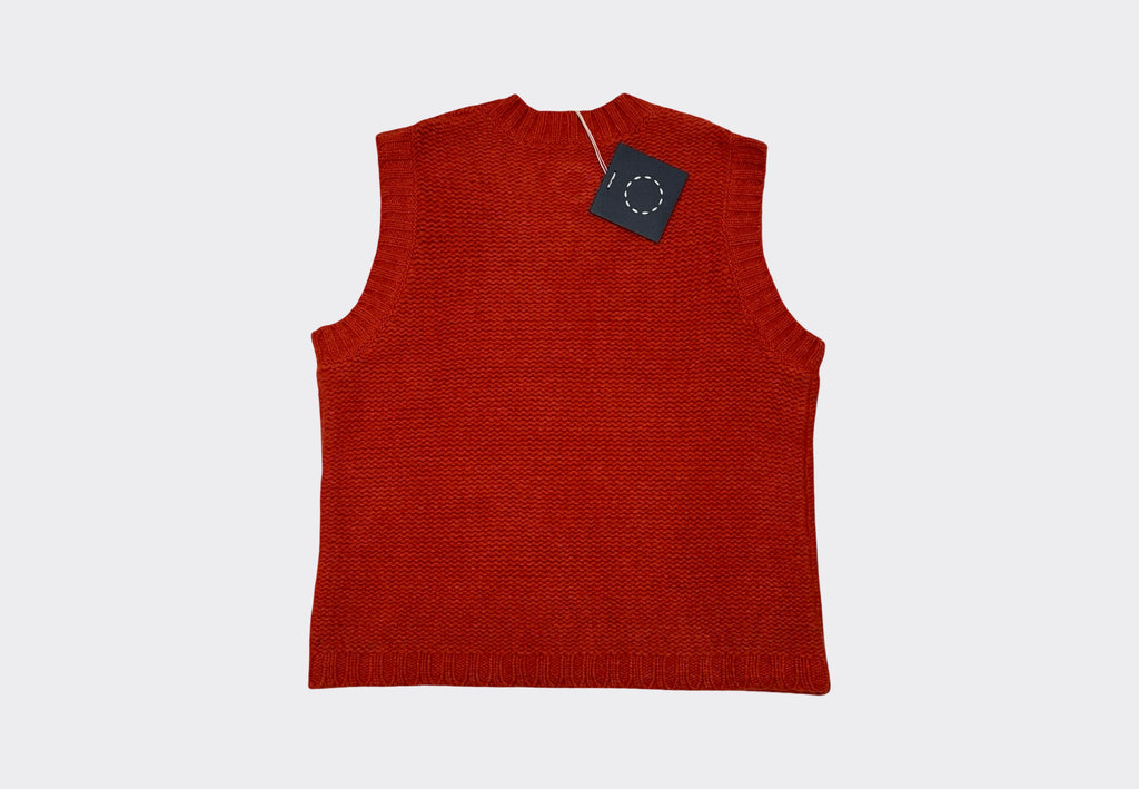 Burnt orange red sleeveless knitted sweater vest with a tag on a light gray background 