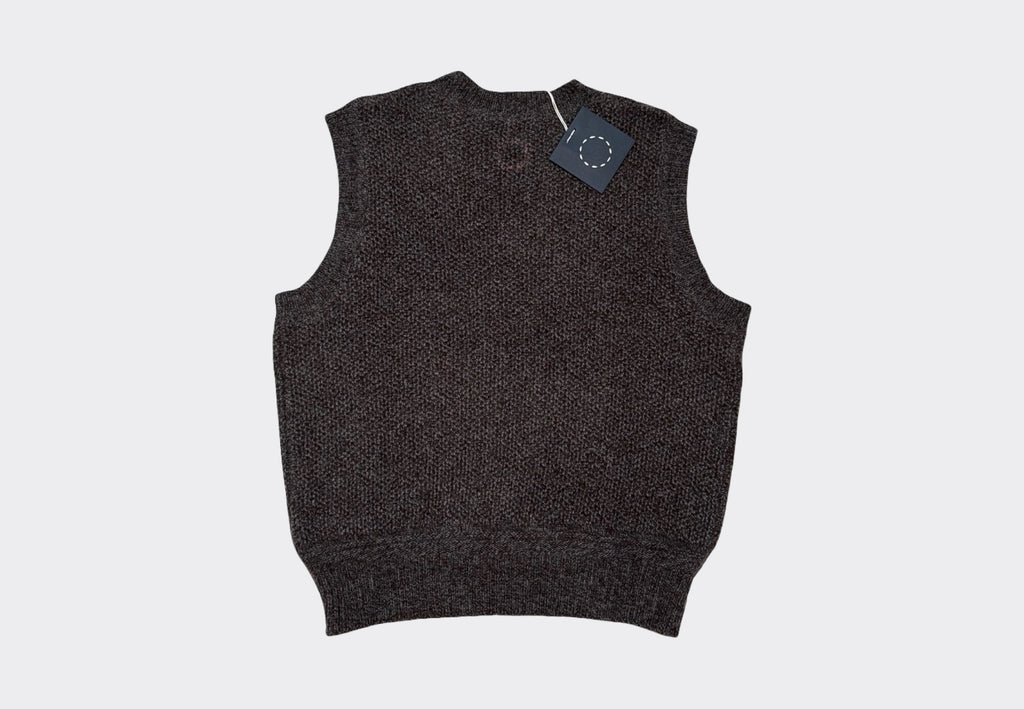 Dark gray knitted vest with a tag on a light gray background