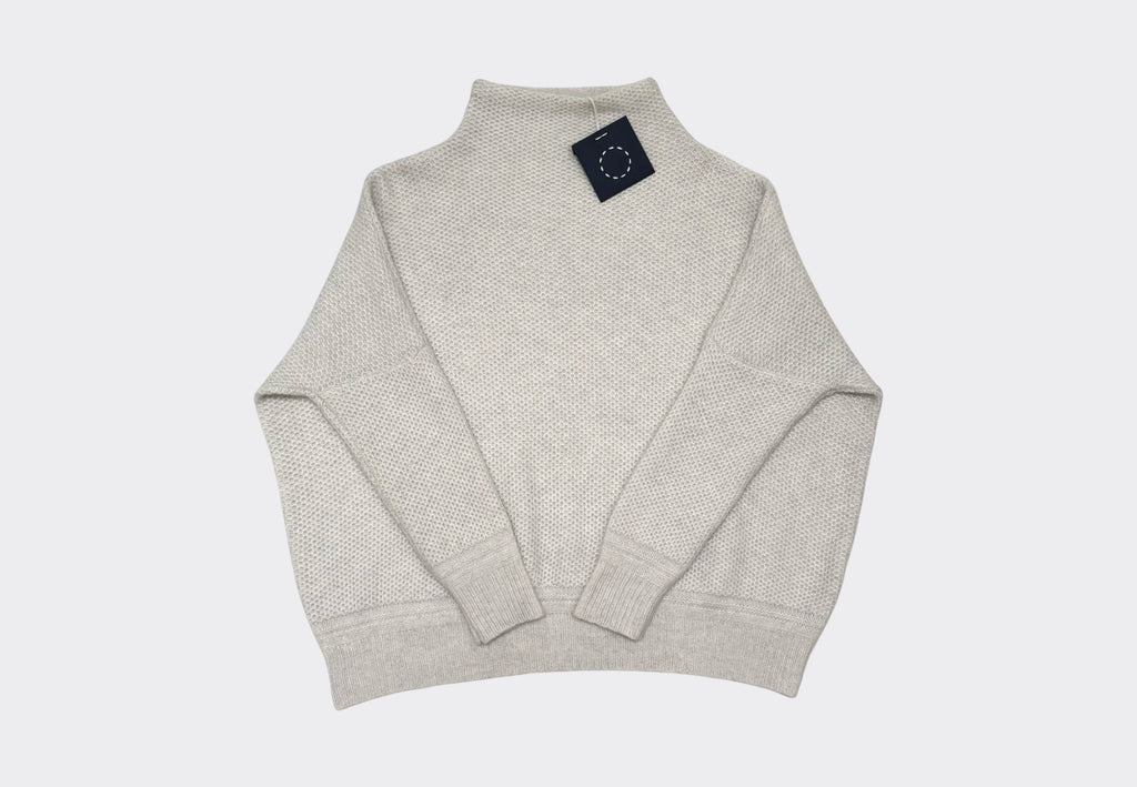 White 5-ply cashmere sweater with a funnel neck, bracelet sleeves, and ribbed hem and cuffs on pale grey background